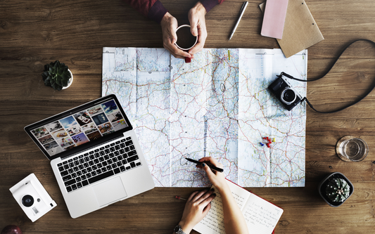 Overhead photo of two people with a map and laptop planning a trip
